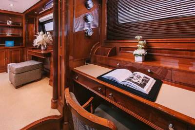 A luxurious wooden desk with an open book and floral arrangement offers a serene workspace on this elegant yacht.