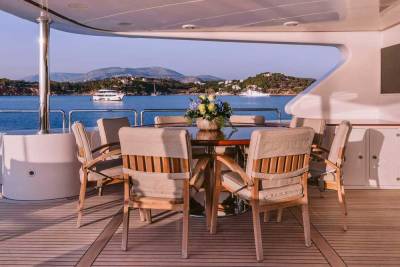 Dine al fresco on this yacht's deck, surrounded by a serene seascape and distant, sun-drenched hills.
