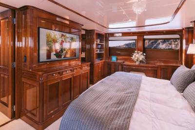 Luxurious wood paneling and a large television create a cozy and elegant master suite aboard this yacht.