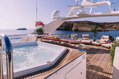 Relax in the bubbling hot tub on the deck of this luxurious yacht, surrounded by stunning ocean views and a rugged coastline.