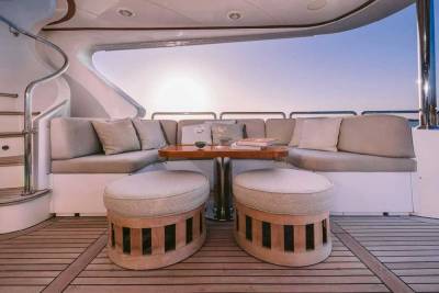 Relax on the plush seating of this luxurious yacht deck, complete with ottomans and a polished wood table.