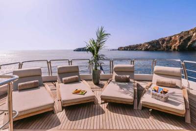 Relax in style on the sun-drenched deck of this luxury yacht, overlooking a rugged coastline.