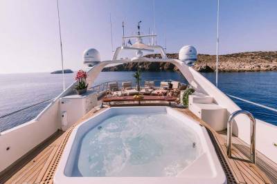 Relax in the bubbling jacuzzi on the deck of this luxurious yacht, surrounded by the serene blue waters and rugged coastline.
