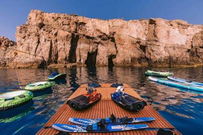 Adventure awaits with inflatable tubes, jet skis, and paddleboards ready for action against a dramatic cliff backdrop.