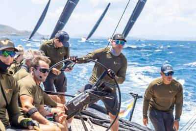 Sailors navigate choppy blue waters under a bright sky as they compete in a regatta.