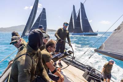 Sailors navigate choppy turquoise waters under a bright blue sky as they race their sleek yachts.