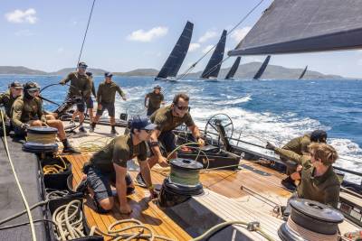 A team of sailors works together on the deck of a yacht, managing the ropes and winches during a race.