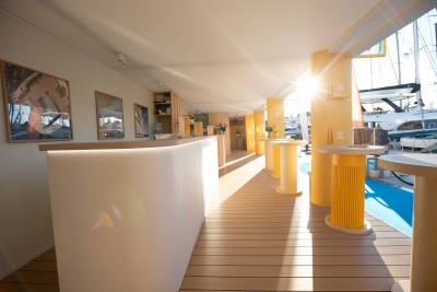 Sunlight streams into a modern reception area overlooking a marina filled with yachts.