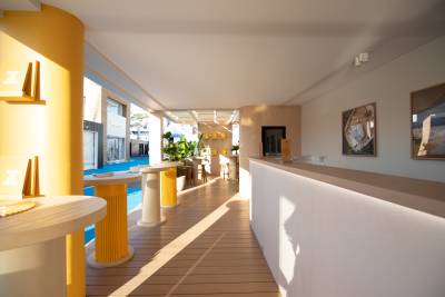 Sunlight streams across a modern outdoor lounge area featuring yellow accents and sleek furniture.