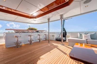 A spacious outdoor deck with a bar area, comfortable seating, and a scenic view of the sky and clouds in the background.