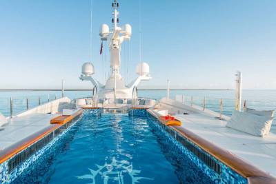 A luxurious yacht features a stunning infinity pool with a sun-drenched deck overlooking the tranquil ocean.