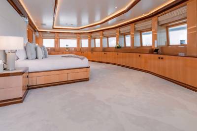 A spacious and luxurious bedroom with a curved wall of wooden cabinetry, a large bed, and a plush white carpet covering the floor.