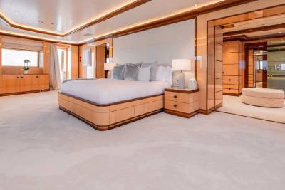 A spacious and luxurious bedroom with a large bed, wooden furniture, and a modern, minimalist design aesthetic.