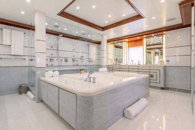 A spacious and luxurious bathroom with a large vanity, recessed lighting, and a tiled floor and walls creating a modern and elegant atmosphere.
