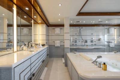 A spacious and modern bathroom with a large vanity, a glass-enclosed shower, and a bathtub, featuring a combination of light and dark tones in the design.