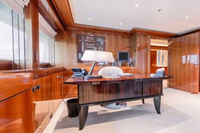 A spacious and well-appointed home office with wooden paneled walls, a large desk, and various office equipment and accessories.