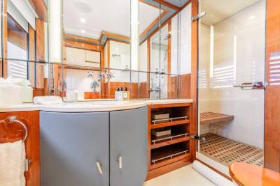 A modern and well-designed bathroom with a vanity, mirror, and storage cabinets in warm wood tones, complemented by a tiled floor and walls.