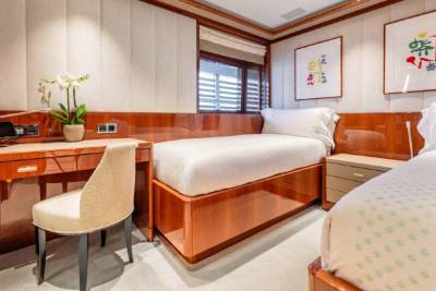 A cozy and well-furnished bedroom with wooden paneling, a comfortable bed, a desk, and decorative elements such as framed artwork and a potted plant, creating a warm and inviting atmosphere.