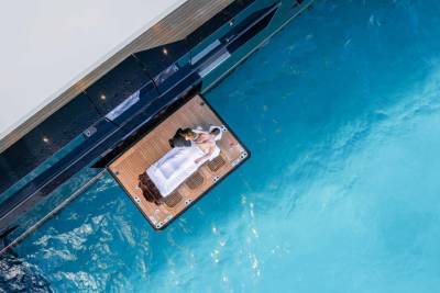 A wooden platform extends over a vibrant turquoise pool, providing a relaxing spot to lounge and enjoy the serene surroundings.