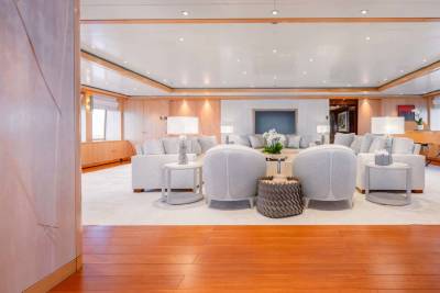 A spacious and elegantly furnished living room with plush white armchairs, a wooden floor, and a warm, inviting atmosphere.