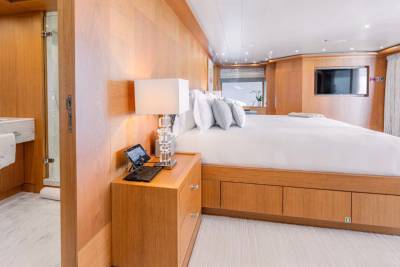 A cozy and modern bedroom with a large bed, wooden furniture, and an en-suite bathroom visible in the background.