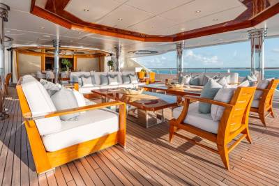 A luxurious outdoor seating area on the deck of a yacht, with comfortable white and orange furniture overlooking the ocean.