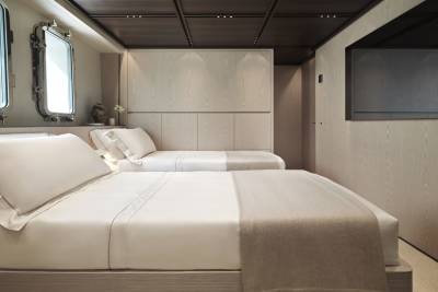 Luxurious twin beds with crisp white linens and warm throws await in this elegantly appointed yacht cabin.