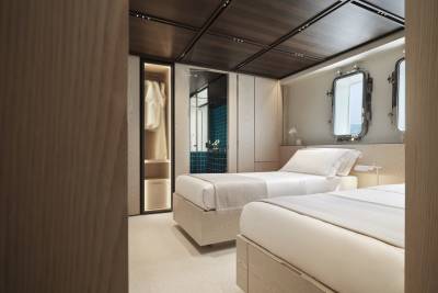 Twin beds with crisp white linens and light wood accents create a serene retreat aboard this luxurious yacht.
