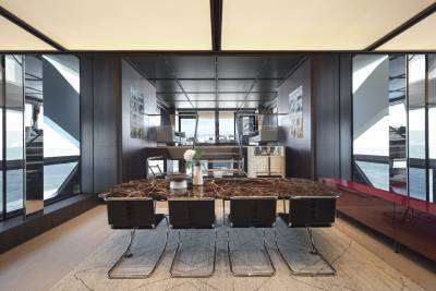 A modern dining area on a yacht features a marble-topped table and sleek chairs with stunning ocean views.