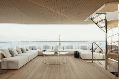 Luxurious white sectional seating and a sleek coffee table create a serene lounge area on this yacht's deck, overlooking the tranquil ocean.