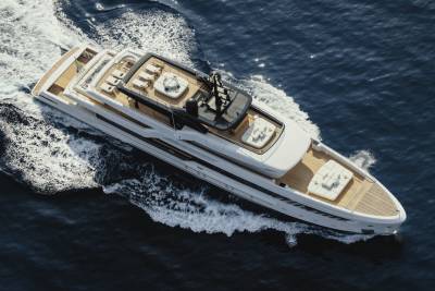 A sleek white yacht glides through the deep blue ocean, leaving a trail of white foam in its wake.