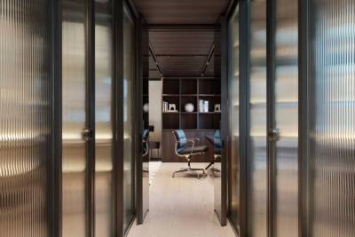 Modern office doors with ribbed glass panels offer a glimpse into a sophisticated workspace with built-in shelving.