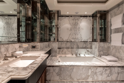 Luxurious marble adorns this opulent bathroom, featuring a deep soaking tub and a sleek vanity.