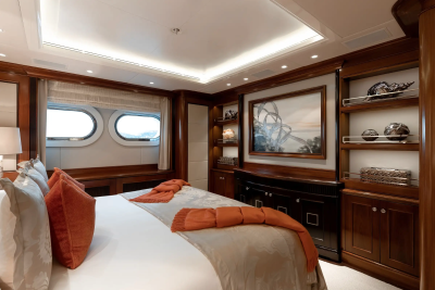 Luxurious yacht cabin features a plush bed, elegant artwork, and porthole windows offering scenic views.