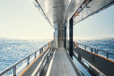 Sunlight glitters on the tranquil blue ocean as seen from the deck of a luxurious yacht.
