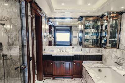 Luxurious marble adorns this opulent bathroom, featuring a sleek shower, elegant vanity, and a deep soaking tub.