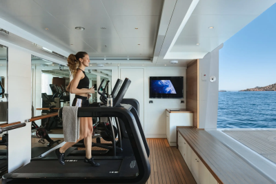 A woman enjoys a scenic run on a treadmill aboard a luxury yacht overlooking the Mediterranean Sea.