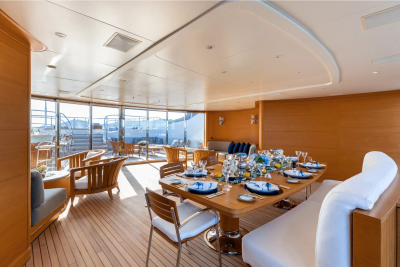 A beautifully set dining table awaits guests on a luxurious yacht's sun-drenched deck.