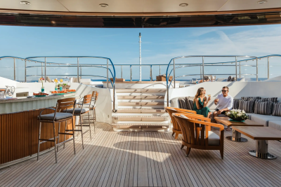 A couple enjoys drinks on the deck of a luxurious yacht, surrounded by the serene blue of the ocean.