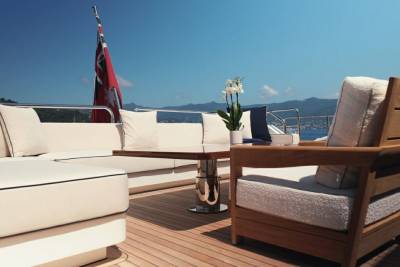 Relax on the luxurious deck of a yacht with plush seating and a stunning view of the coastline.