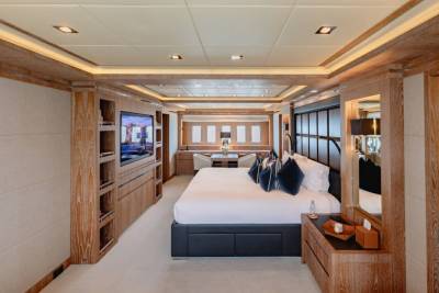 Luxurious yacht interiors feature a spacious master suite with a king-sized bed, entertainment system, and elegant wood finishes.