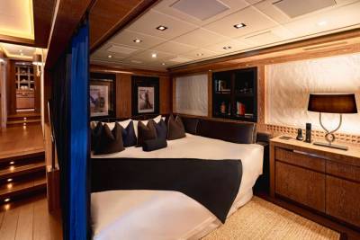 A luxurious yacht cabin features a plush bed, elegant wood paneling, and sophisticated decor.