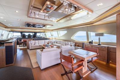 Luxurious yacht interiors feature plush white sofas, warm wood accents, and expansive windows offering breathtaking ocean views.