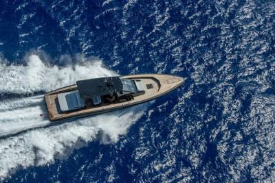 A sleek yacht cuts through the deep blue ocean, leaving a trail of white foam in its wake.