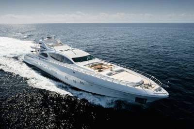 A sleek white yacht cuts through the deep blue ocean, leaving a trail of white foam in its wake.