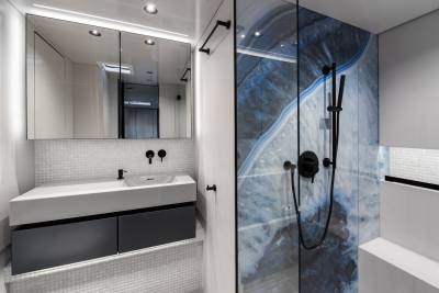 A modern bathroom with a sleek vanity, a large mirror, and a striking blue marble-patterned shower enclosure.