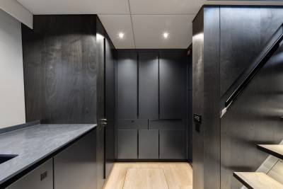 A modern, minimalist kitchen with dark wood cabinets, a marble countertop, and recessed lighting creating a sleek and sophisticated atmosphere.