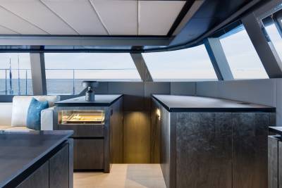 A modern and sleek kitchen with a panoramic view of the ocean, featuring dark cabinets, a stainless steel appliance, and a cozy seating area.