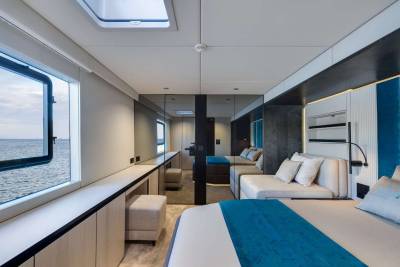 A modern and spacious cabin interior with large windows offering a scenic view of the ocean in the background.