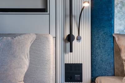 A cozy living room with a gray sofa, a black wall-mounted lamp, and blue curtains in the background.